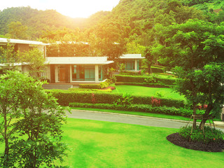 The evening sun shines over a modern house with a lawn and garden.