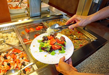 customer  serving himself from trays with vegetables