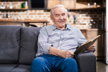 Joyful senior man reading with pleasure