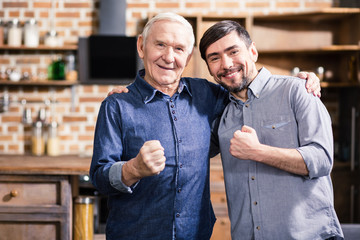 Positive elderly man embracing with his son