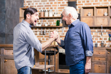 Positive aged man and his son practicing arm wrestling