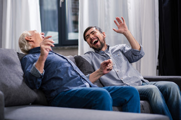 Overjoyed son and elderly father making jokes
