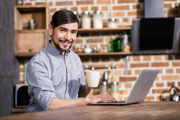 Waist up of cheerful man using his laptop