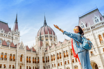 Obraz premium Happy asian casual woman student enjoying great view of the Parliament building in Budapest city, travel in Europe concept