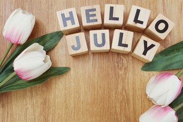 hello july with artificial flower on wooden background