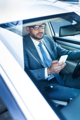 portrait of businessman with smartphone driving car
