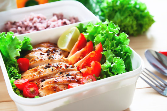 Grilled chicken breast with tomatoes, lettuce and steam rice in food container. Close up, Healthy lifestyle concept