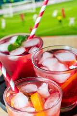 aperitif in the sports bar during a football match: Negroni cocktail with Campari, ice and orange slices, green and black olives