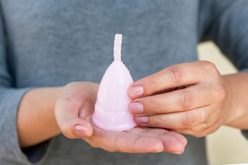 The menstrual cup is holding by woman hands. Selective focus.