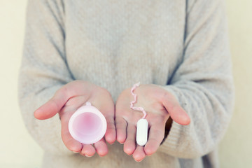 Tampon or Menstrual cup? The Fem cup and tampon holds a feminine hand. Selective focus.