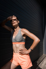 young tired sportswoman posing in sportswear with fitness tracker