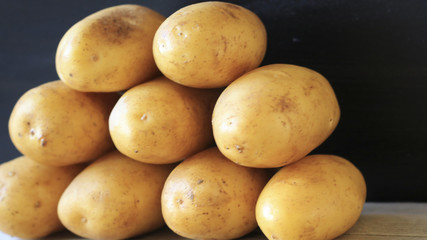 Raw young potatoes in a peel on a black background