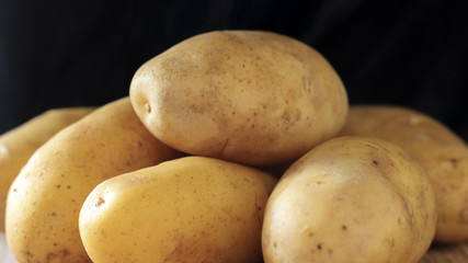 Raw young potatoes in a peel on a black background