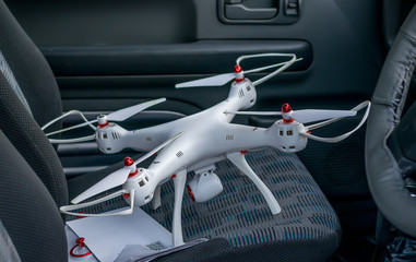 the quadcopter is standing on the car passenger seat with the instruction and remote