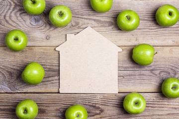 House symbol with green apples on old wooden background. Place for text.