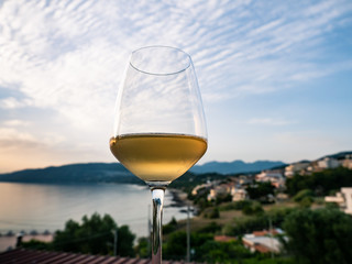 a glass of white wine with seascape at sunset