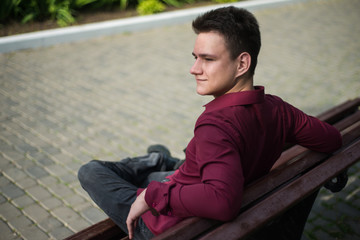 A young man sits on a bench, waiting for someone