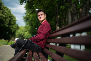 A young man sits on a bench, waiting for someone