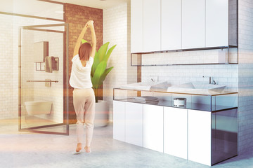 White sink in a brick bathroom corner, woman