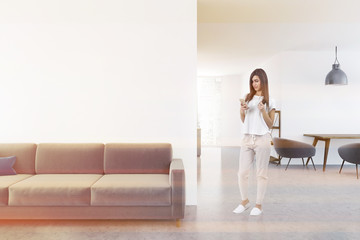 White living room interior, sofa, smartphone woman