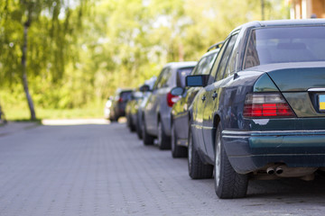 Long row of cars parked in quiet neighborhood on clean empty paved street on background of...