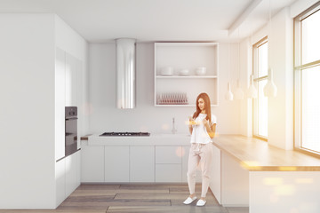 Woman in a white minimalist kitchen interior
