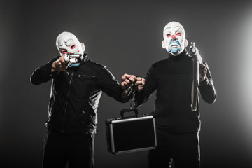 two robbers holding a case and a weapon