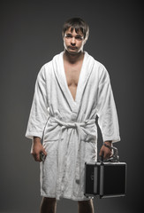 man in a white robe holding a case and a grenade