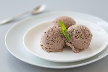 Bowl of chocolate ice cream with mint on white background. 