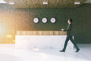 Gray office waiting room, reception, clocks, man