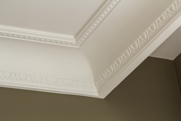 Ornamental white molding decor on ceiling of white room close-up detail. Interior renovation and...