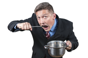 Businessman eats with a spoon from an open pan looking up isolated on a white background