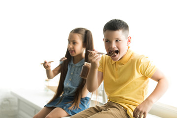 siblings eating chocolate together in kitchen