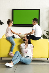 children eating popcorn and mother sitting tied with rope on floor at home