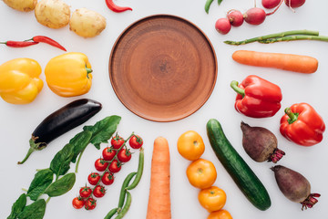 top view of empty round plate and fresh ripe vegetables isolated on white