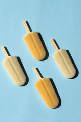 Lemon and milk popsicles on a turquoise background. Flat lay of summer sweets in pop-art style. Vertical format 
