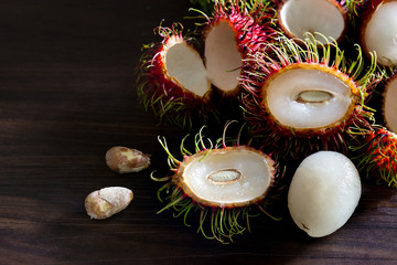 Fototapeta na wymiar Fresh Rambutans and pile of rambutans fresh from the garden with peeled and seed on wooden ground, Thai fruit