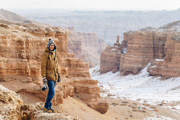 A cheerful traveler with a camera stands on the edge of the cliff in the Charyn canyon in Kazakhstan. Analogue of the American Grand Canyon.