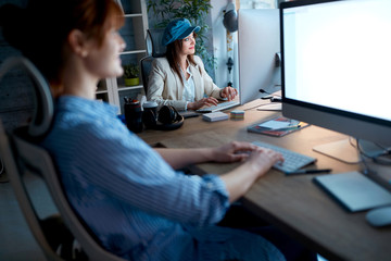Obraz premium Modern woman designer smiling and working overtime at workplace.
