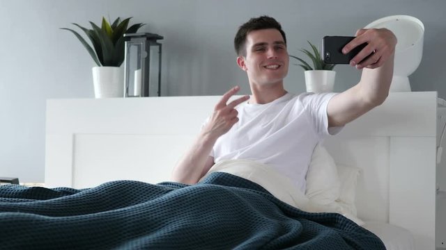 Man Taking Selfie with Smartphone in Bed