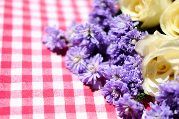 White roses and Purple Marguerite Daisy flowers on red checkered tablecloth in green bokeh nature garden background.Ultra violet for 2018.Use for Valentine day and holiday concept.Copy space.