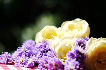 White roses and Purple Marguerite Daisy flowers on red checkered tablecloth in green bokeh nature garden background.Ultra violet for 2018.Use for Valentine day and holiday concept.Copy space.