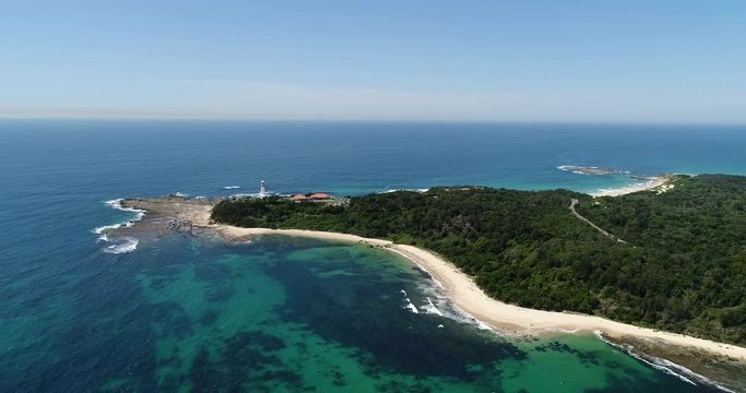 Australian NSW central coast from Norah lighthouse on a rocky head panning along sandy beach and gumtree covered reserve towards town.
