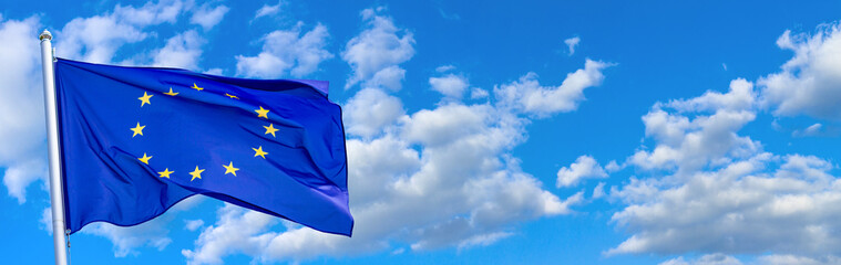 Flag of the European Union waving in the wind on flagpole against the sky with clouds on sunny day,...