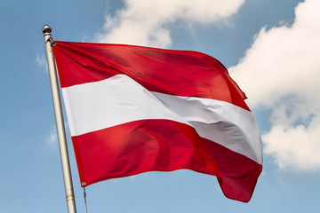 Flag of Austria waving in the wind on flagpole against the sky with clouds on sunny day, close-up - obrazy, fototapety, plakaty