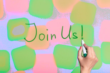 A female hand writing Join Us