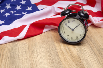National flag of America and black alarm clock on old wooden background