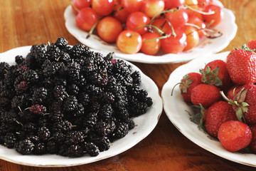 Fruits on a plate. Berries. Strawberry, cherry and mulberry