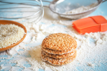 top view of product set for cooking cookies, kitchenware and several round cookies with sesame on a blue wooden table