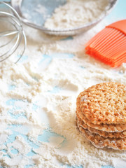top view of product set for cooking cookies, kitchenware and several round cookies with sesame on a blue wooden table